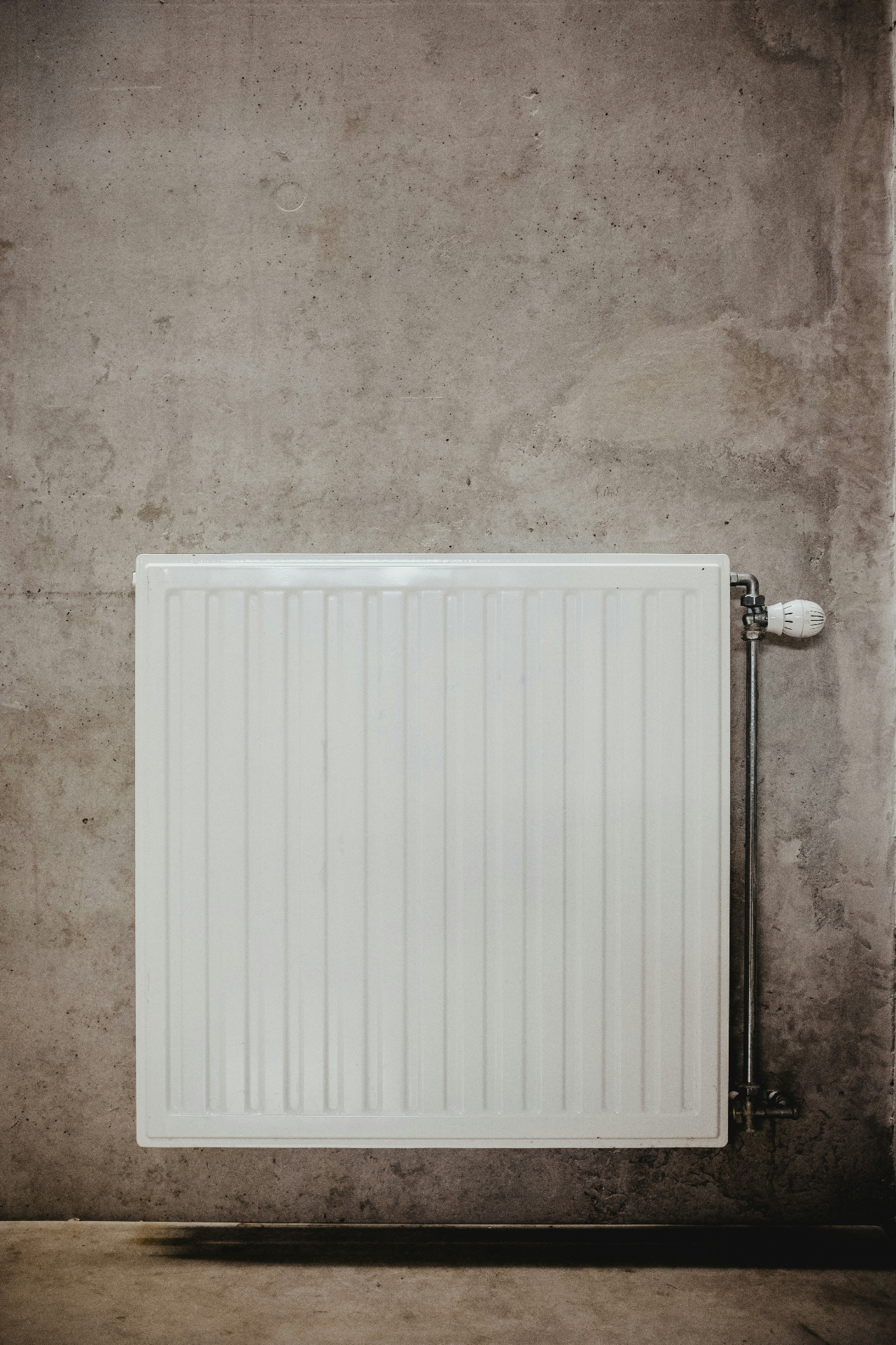 Witte radiator tegen betonnen muur